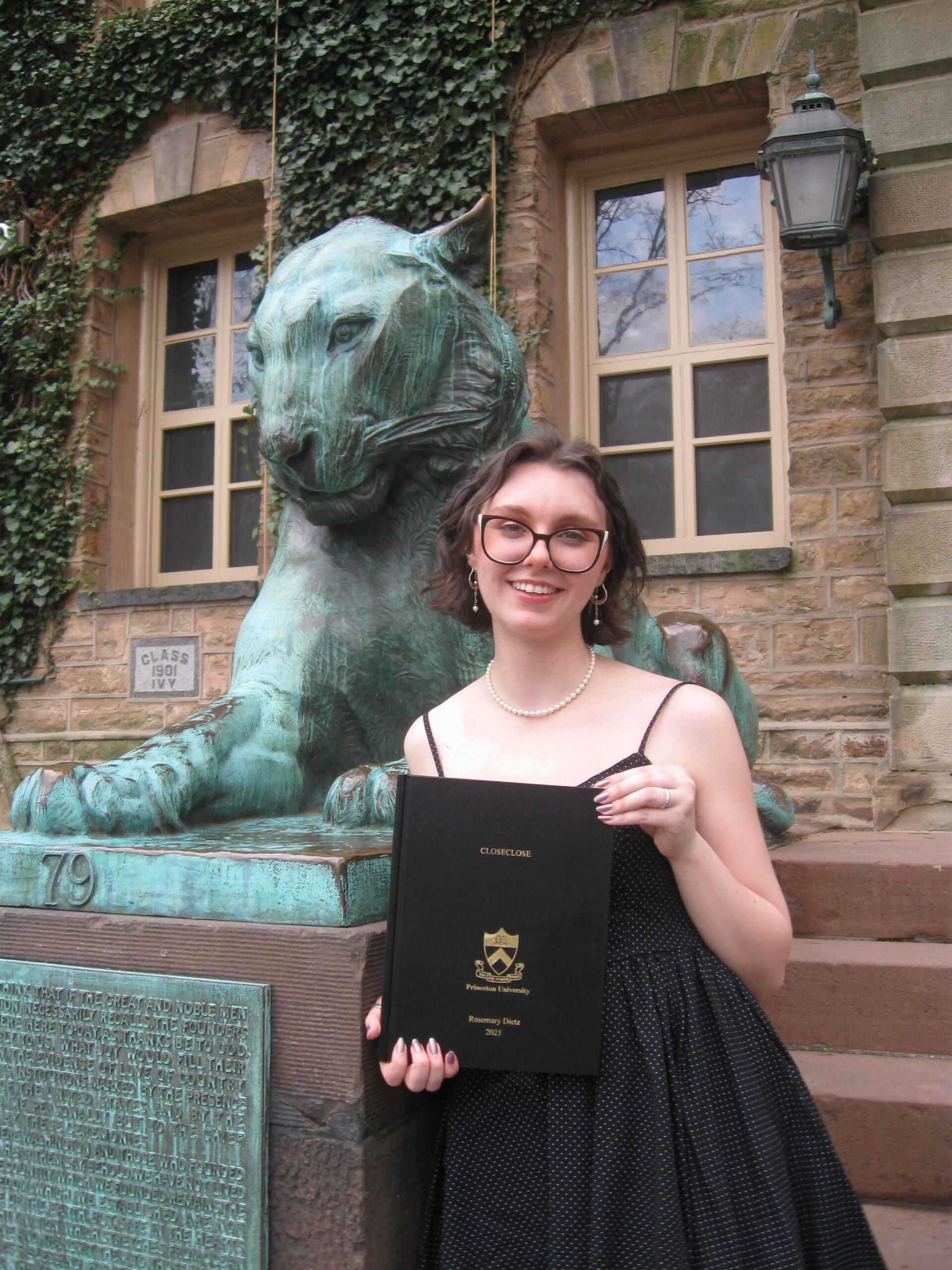 A photo of Madelyn Dietz holding her senior poetry thesis in front of Nassau Hall in Princeton, New Jersey.
